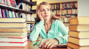 Bored girl sitting among a stack of books