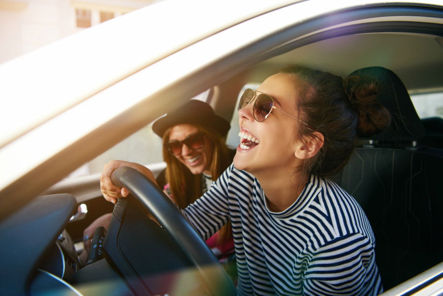 Two friends laughing while driving in a car together