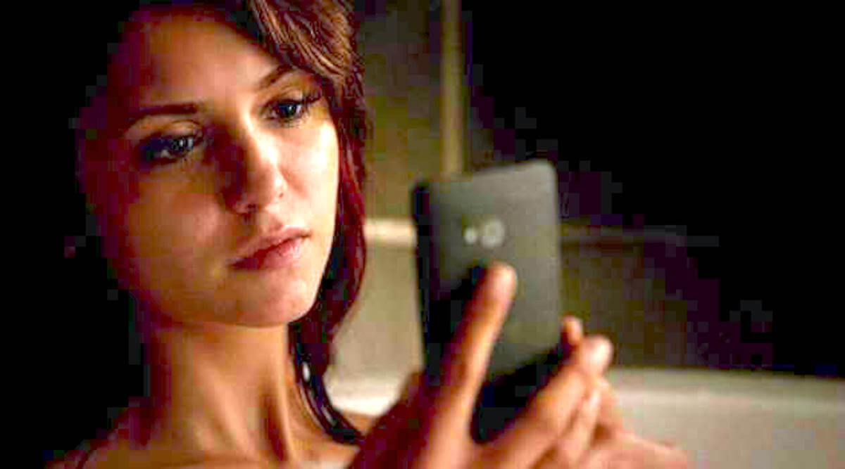 Elena Gilbert staring sadly at her phone on The Vampire Diaries
